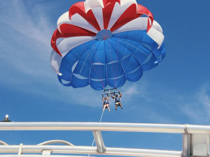 Due persone in volo con il paracadute sopra il mare