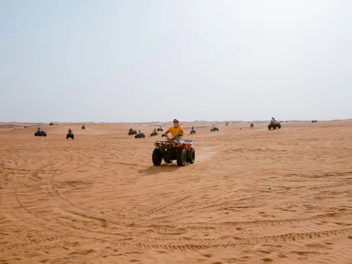 Quad in fila nel deserto sabbioso
