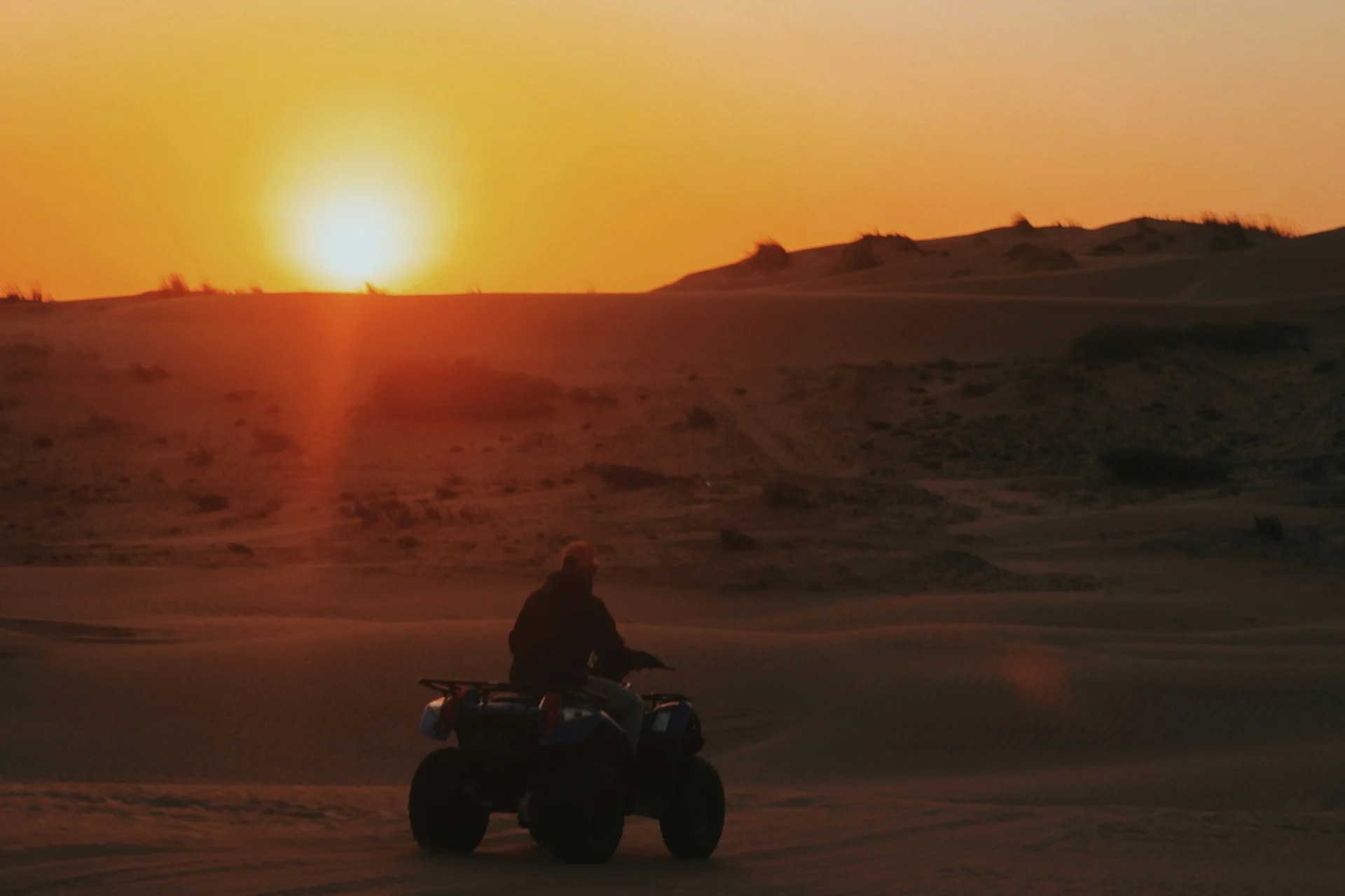 Quad singolo tra le dune al tramonto